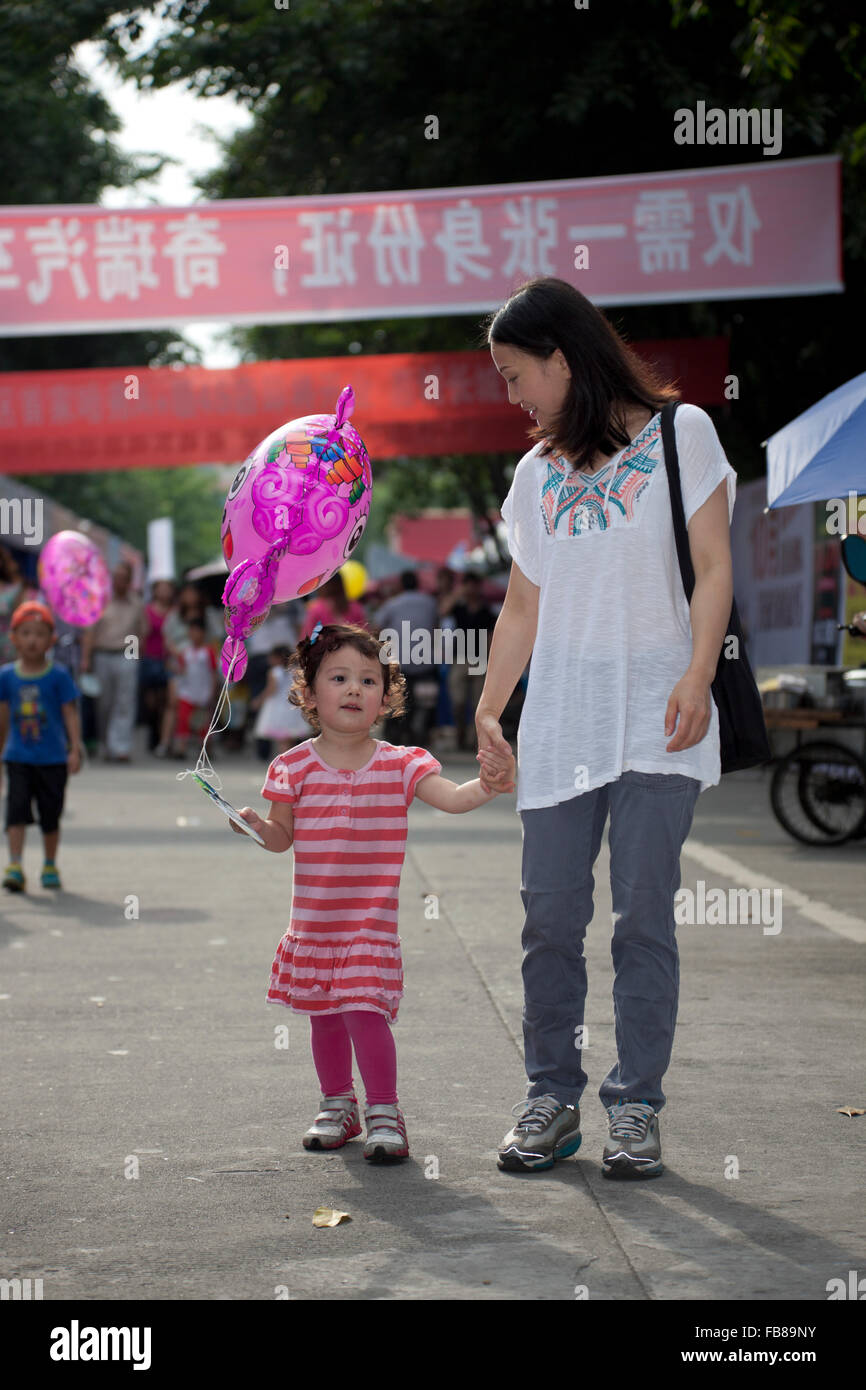 Un misto di gara bimbo e sua madre cinese a una fiera commerciale in una città in Cina. Foto Stock