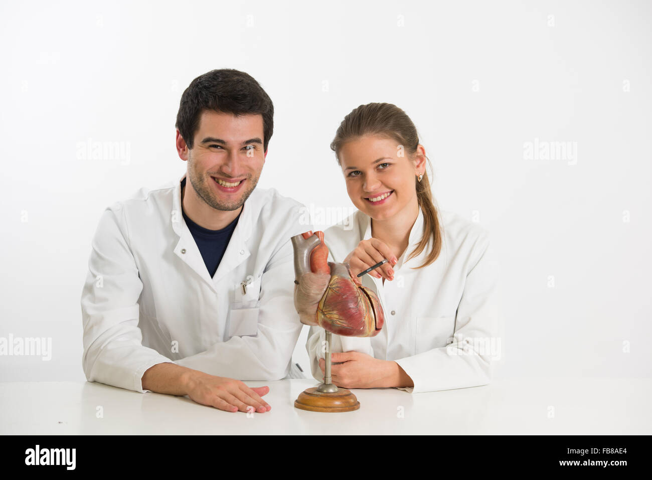 Coppia di giovani medici, uomo e donna, con il modello del cuore umano Foto Stock