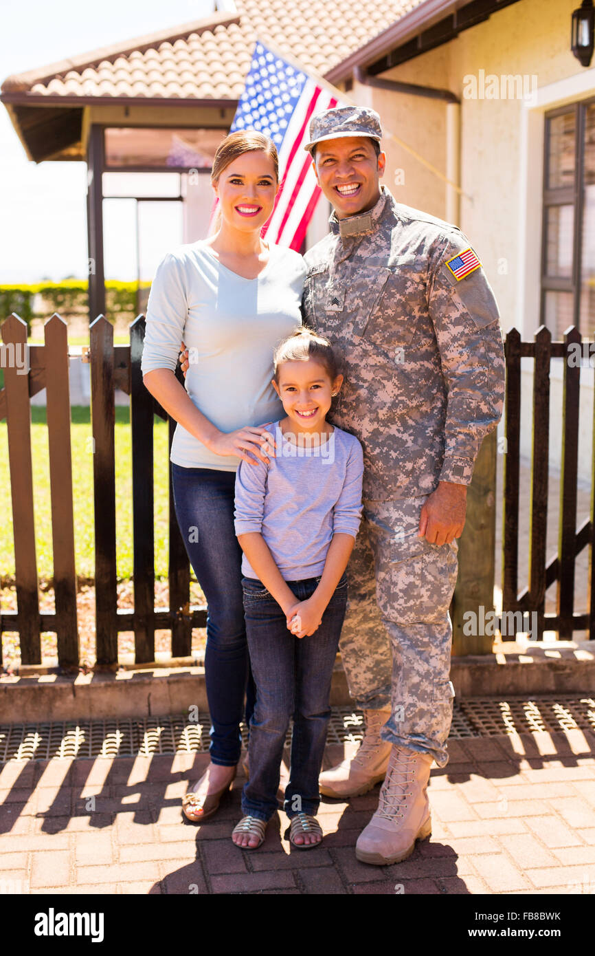 Allegro giovane famiglia militare in piedi insieme davanti alla loro casa Foto Stock