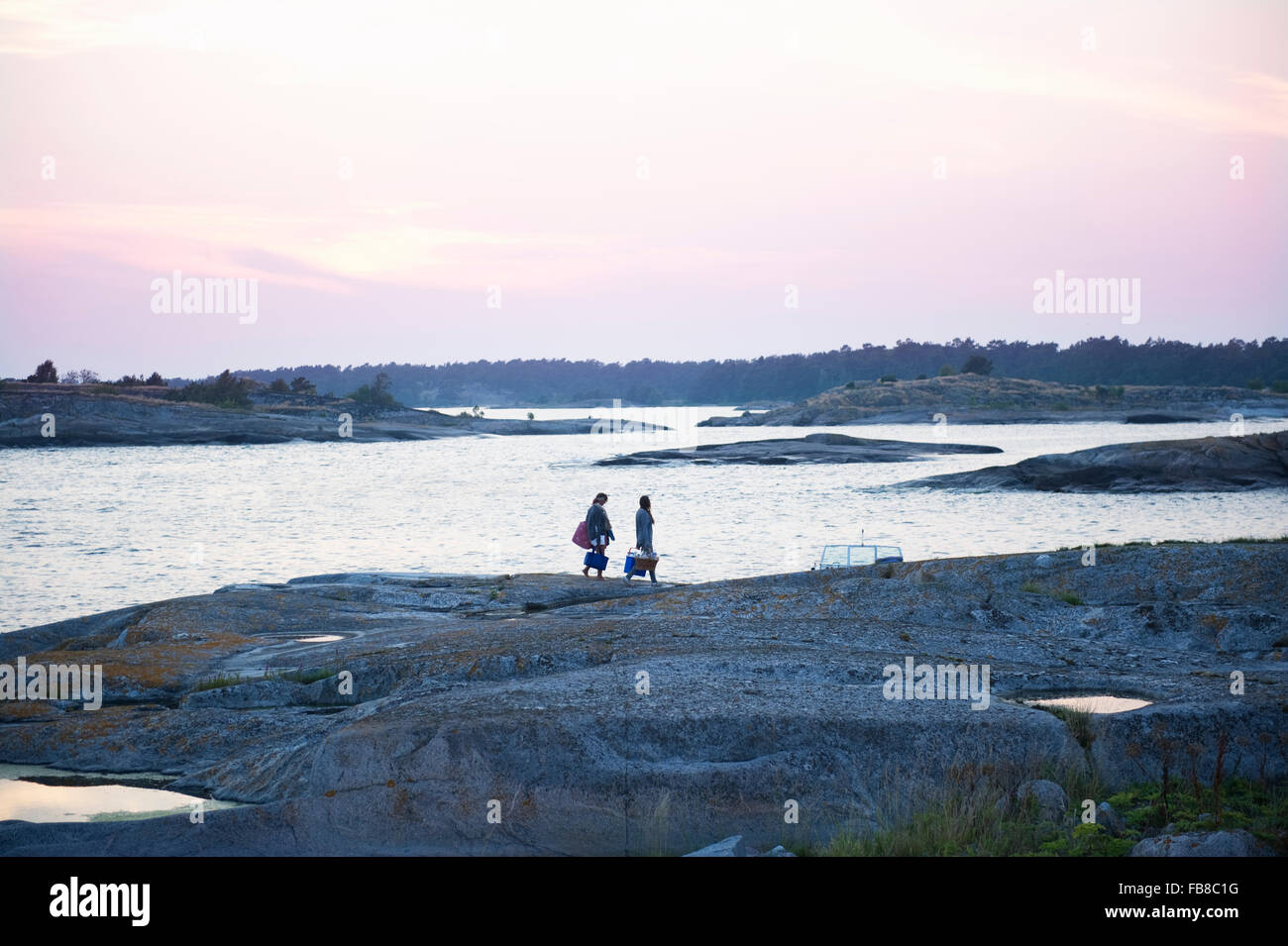La Svezia, Stoccolma, Skargard Sodermanland, Varmdo, Villinge, due donne camminando sulla roccia lungo mare Foto Stock
