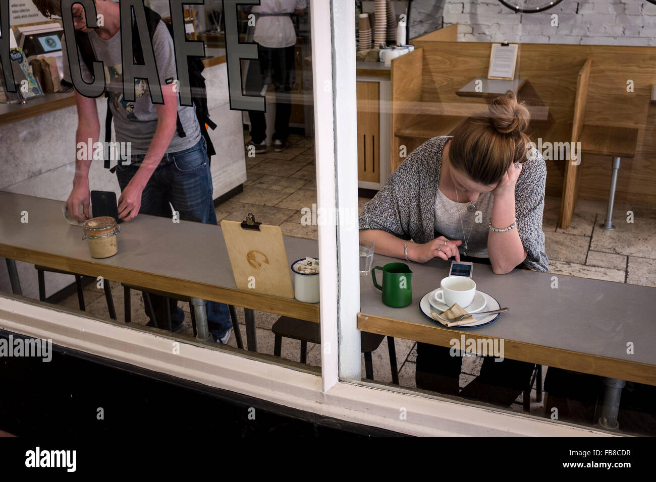 Una femmina utilizzando un telefono cellulare in un cafe, REGNO UNITO Foto Stock