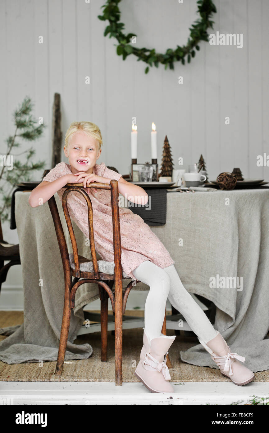 La Svezia, giovane ragazza (6-7) seduti su una sedia in soggiorno durante il periodo di Natale Foto Stock
