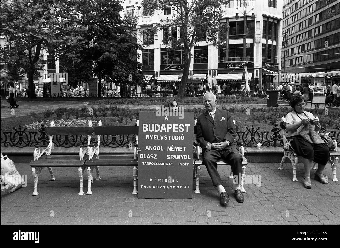 Sguardo su Bupapest al tempo degli anni Novanta. - 1990 - Ungheria / Budapest - sguardo su Bupapest al tempo degli anni Novanta. - Della vita quotidiana scena. In un giardino pubblico è una donna maglia mentre un uomo è a fianco a fianco con una ragazza con un avviso pubblicitario per un insegnamento delle lingue straniere a scuola. - Philippe Gras / Le Pictorium Foto Stock