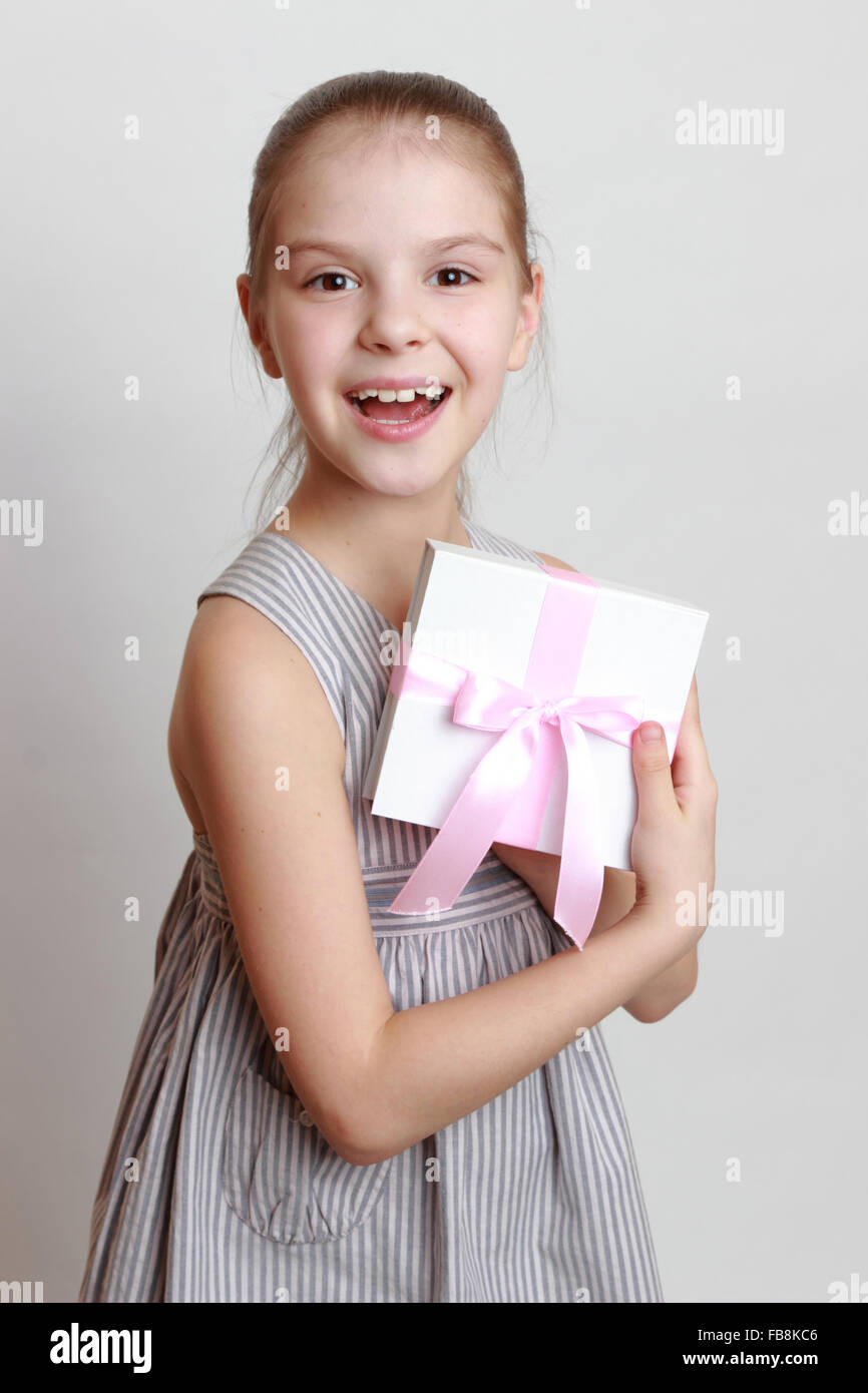 Bella sorridente bambina azienda scatola regalo bianca con nastro rosa Foto Stock