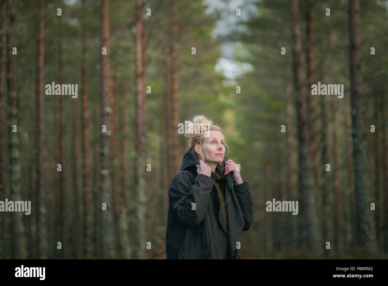 Una donna a piedi attraverso una foresta Foto Stock