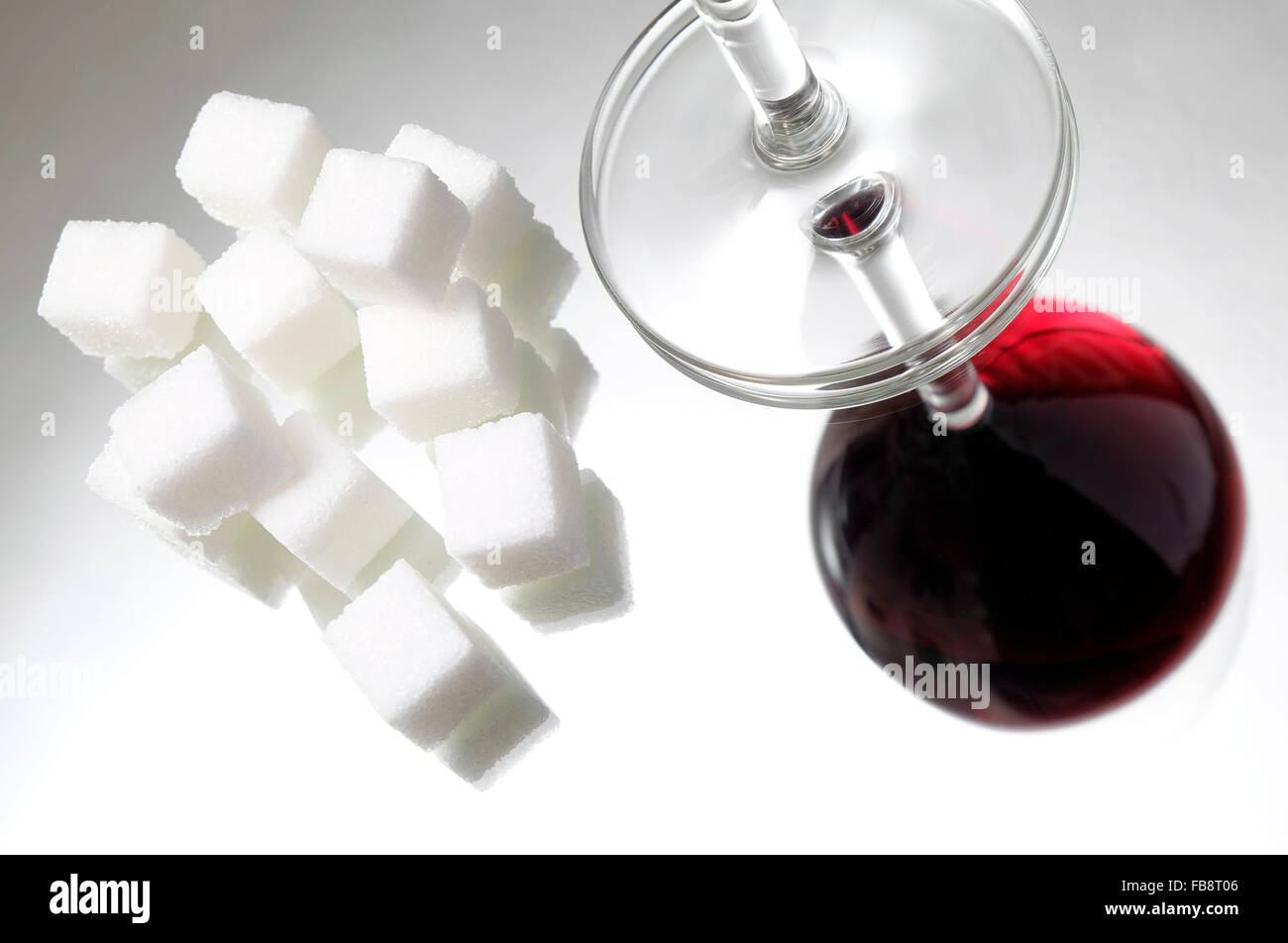 Lo zucchero cristallizzato bianco cubi e bicchiere di vino rosso Foto Stock