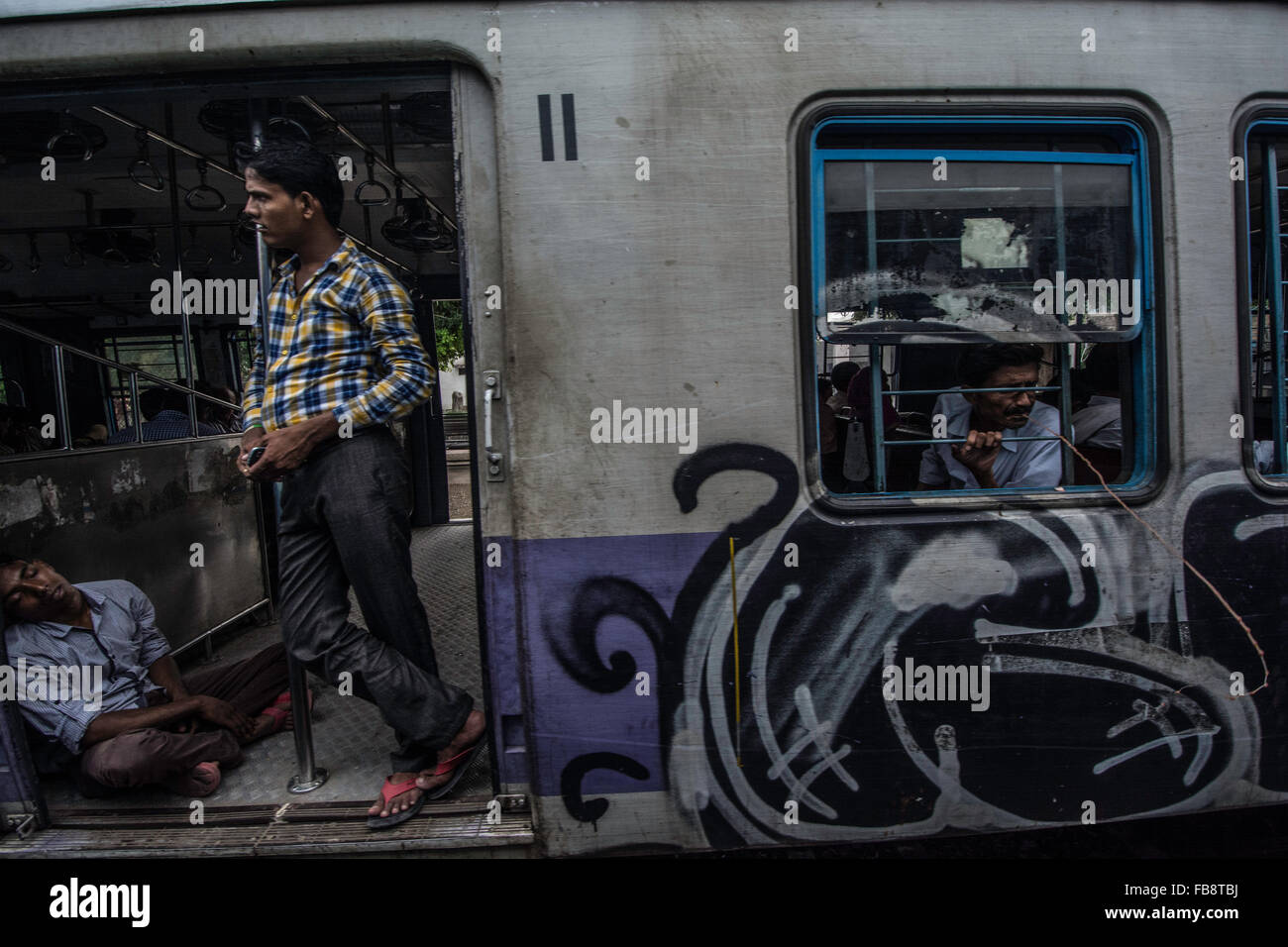 Passeggeri guardando fuori della porta su un treno indiano. Foto Stock