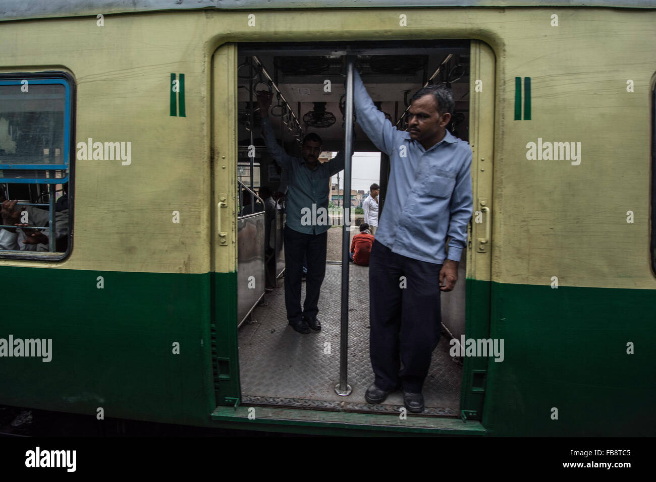 Passeggeri guardando fuori della porta su un treno indiano. Foto Stock