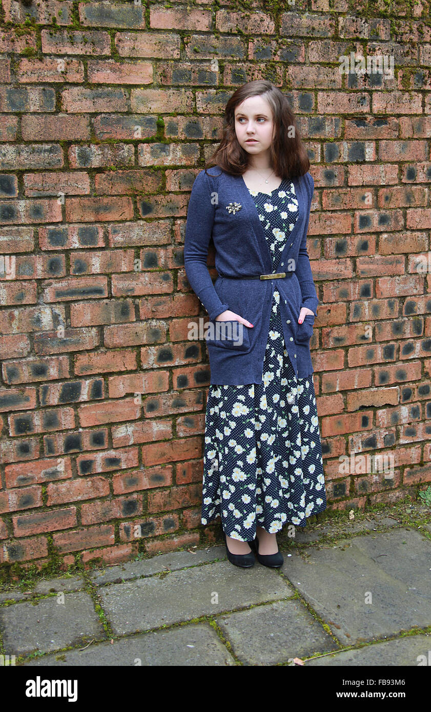 Giovane donna in piedi contro un muro di mattoni vestito in stile anni 1940 Foto Stock
