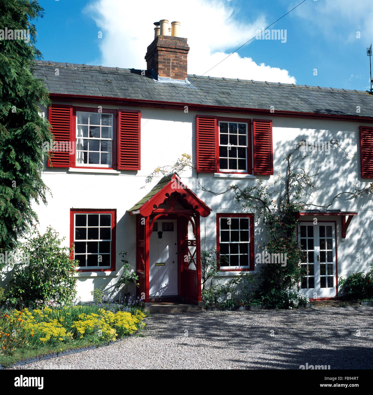 Esterno di un cottage di bianco con persiane rosse e veranda Foto Stock