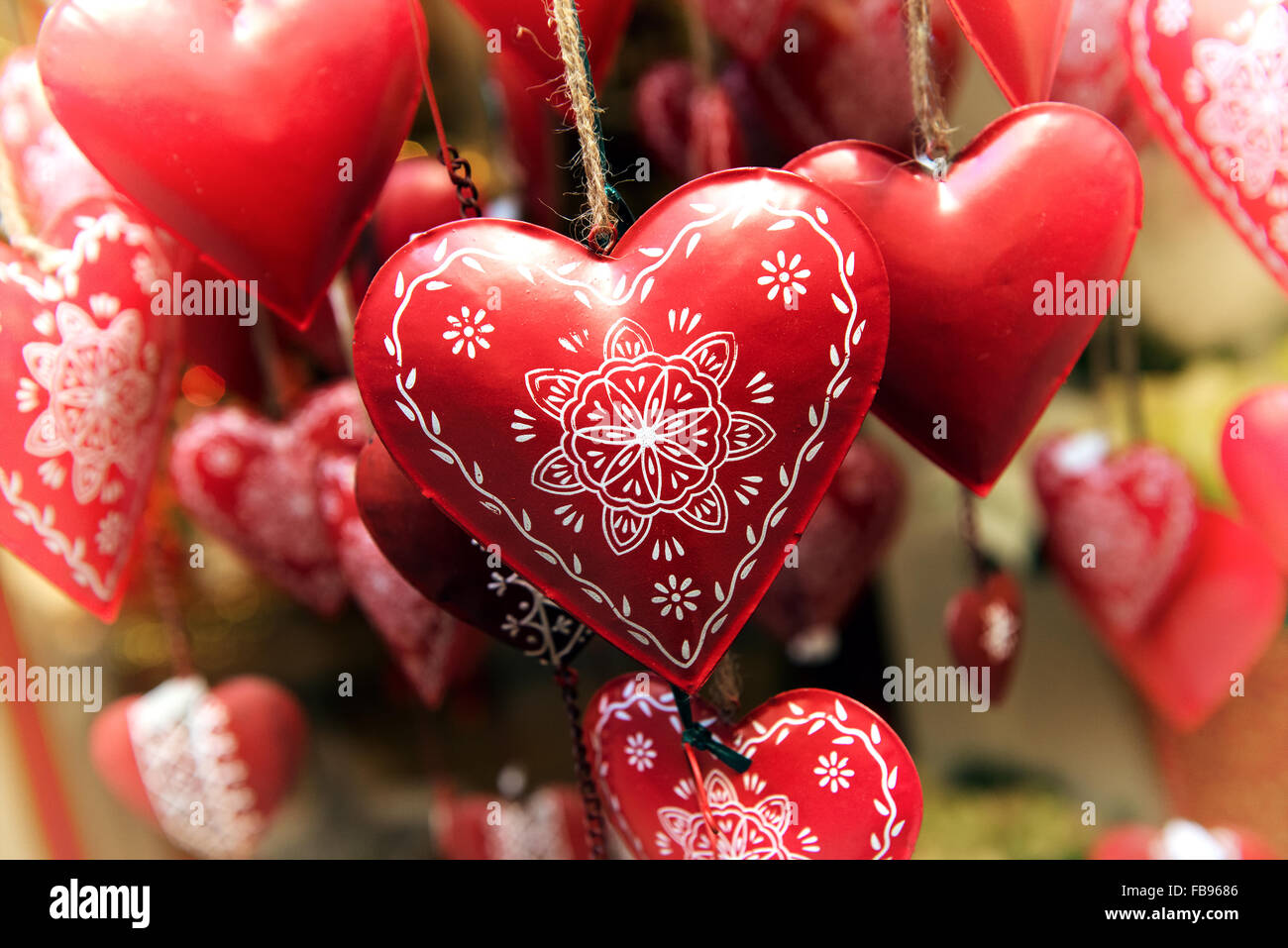 Appendere rosso metallo decorato cuori simbolici di amore e romanticismo per Natale, Anniversario o il giorno di San Valentino, vista ravvicinata Foto Stock