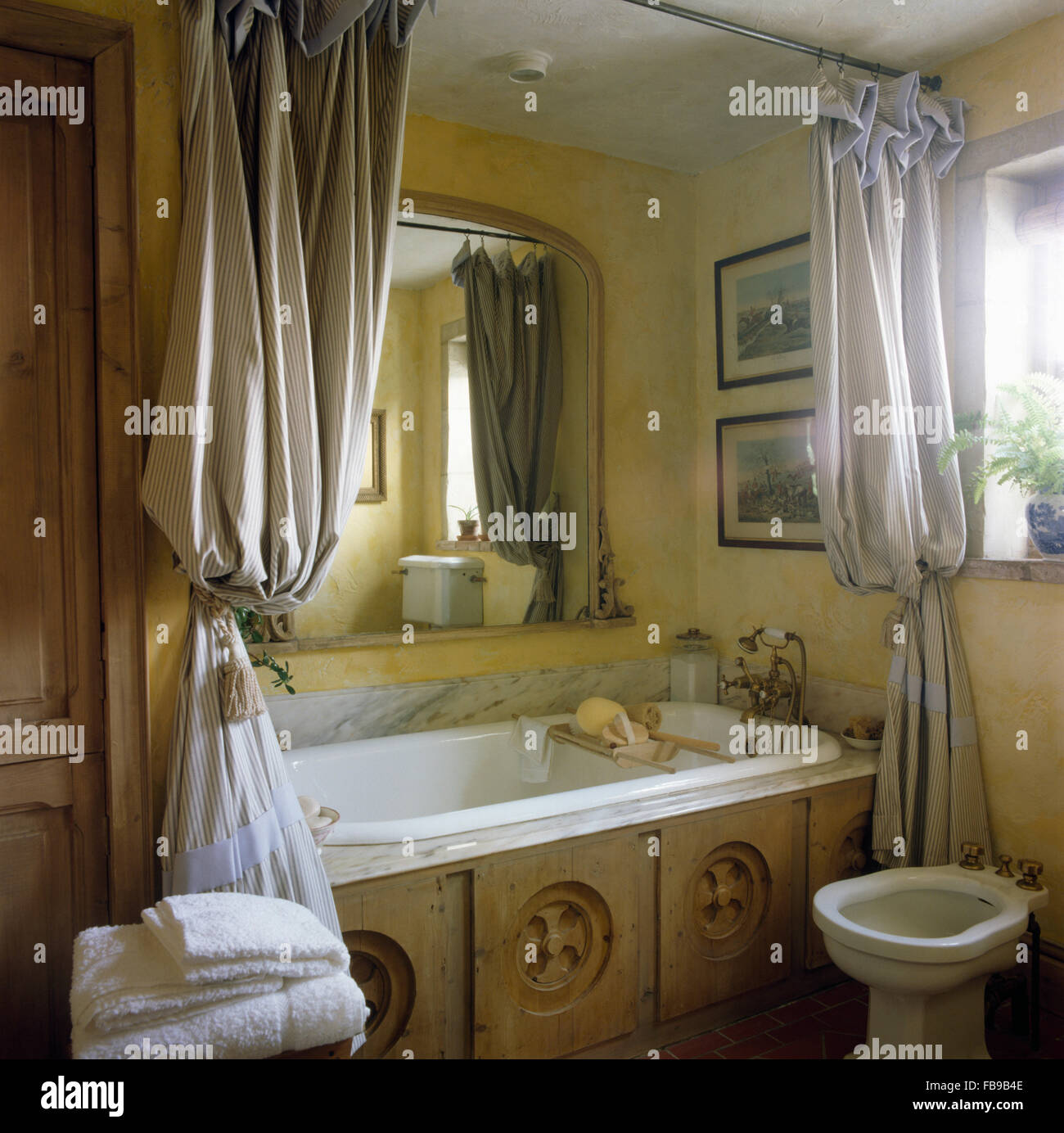Striped tende da doccia su vasca da bagno con bonificata in legno scolpito nel pannello degli anni ottanta Bagno con bidet Foto Stock