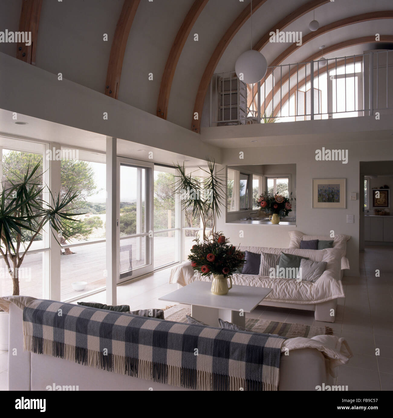 Divani bianchi in una grande altezza doppia soggiorno con un piano mezzanino e una parete di vetro Foto Stock