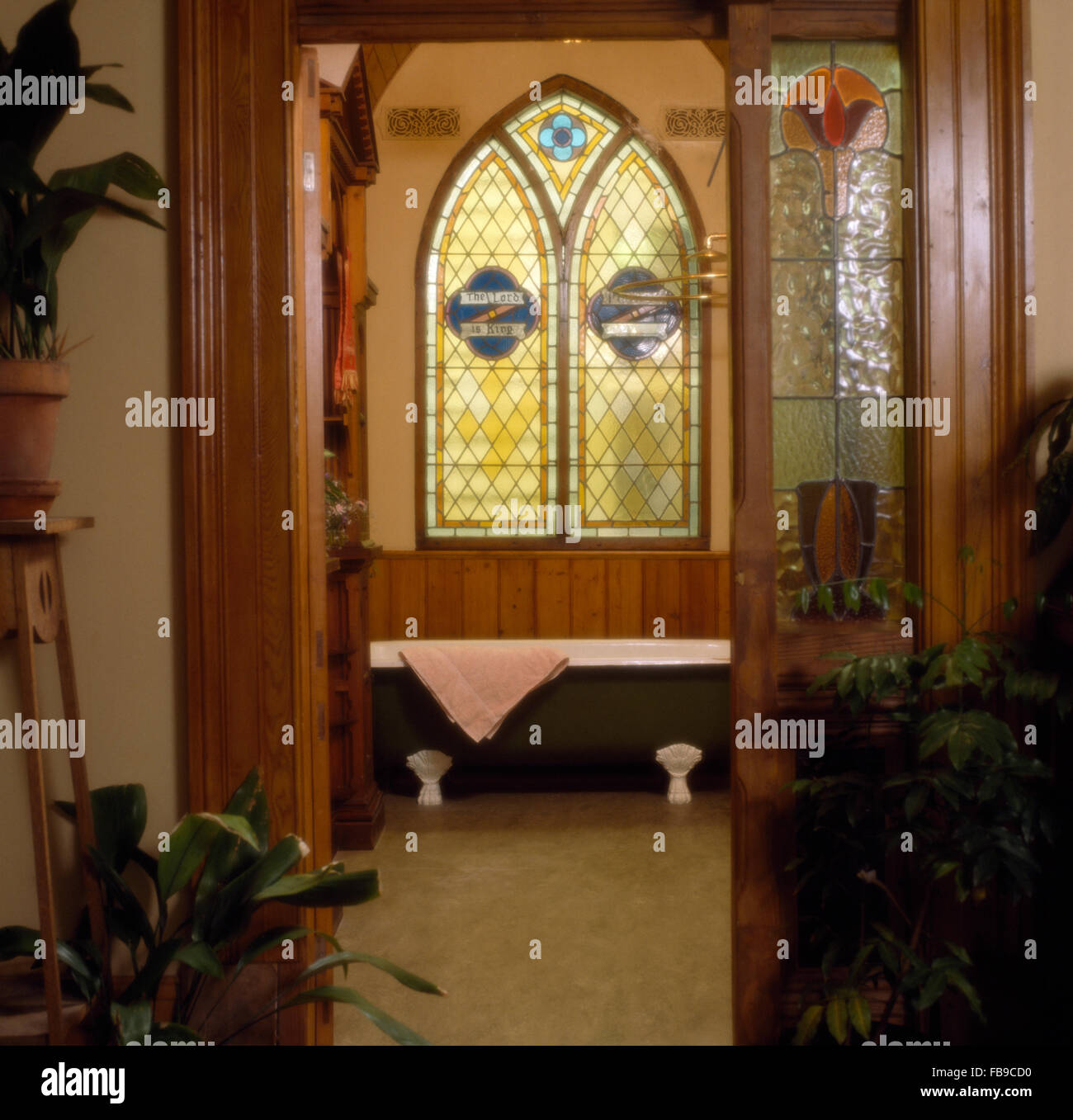 In vetro colorato stile gotico finestra sopra roll top bagno in bagno retrò Foto Stock
