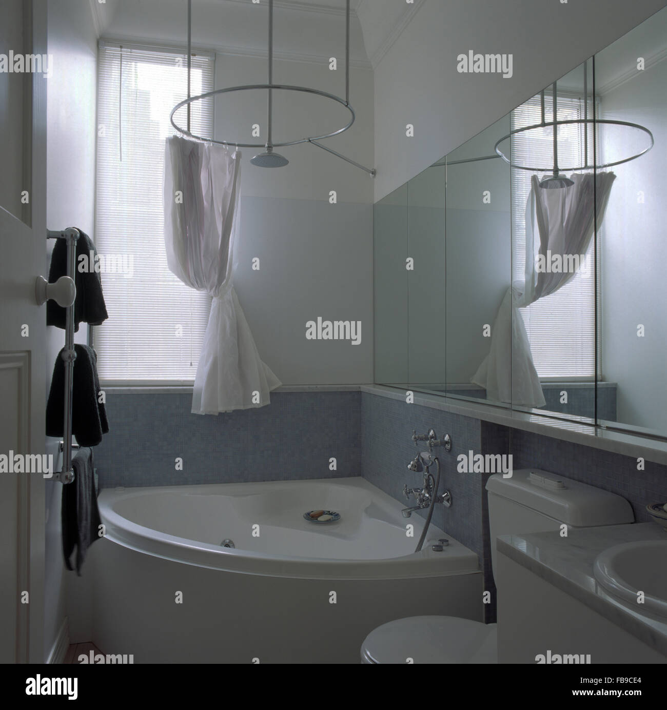 Drappi bianchi circolare su rotaia doccia sopra la vasca angolare degli anni novanta in bagno Foto Stock