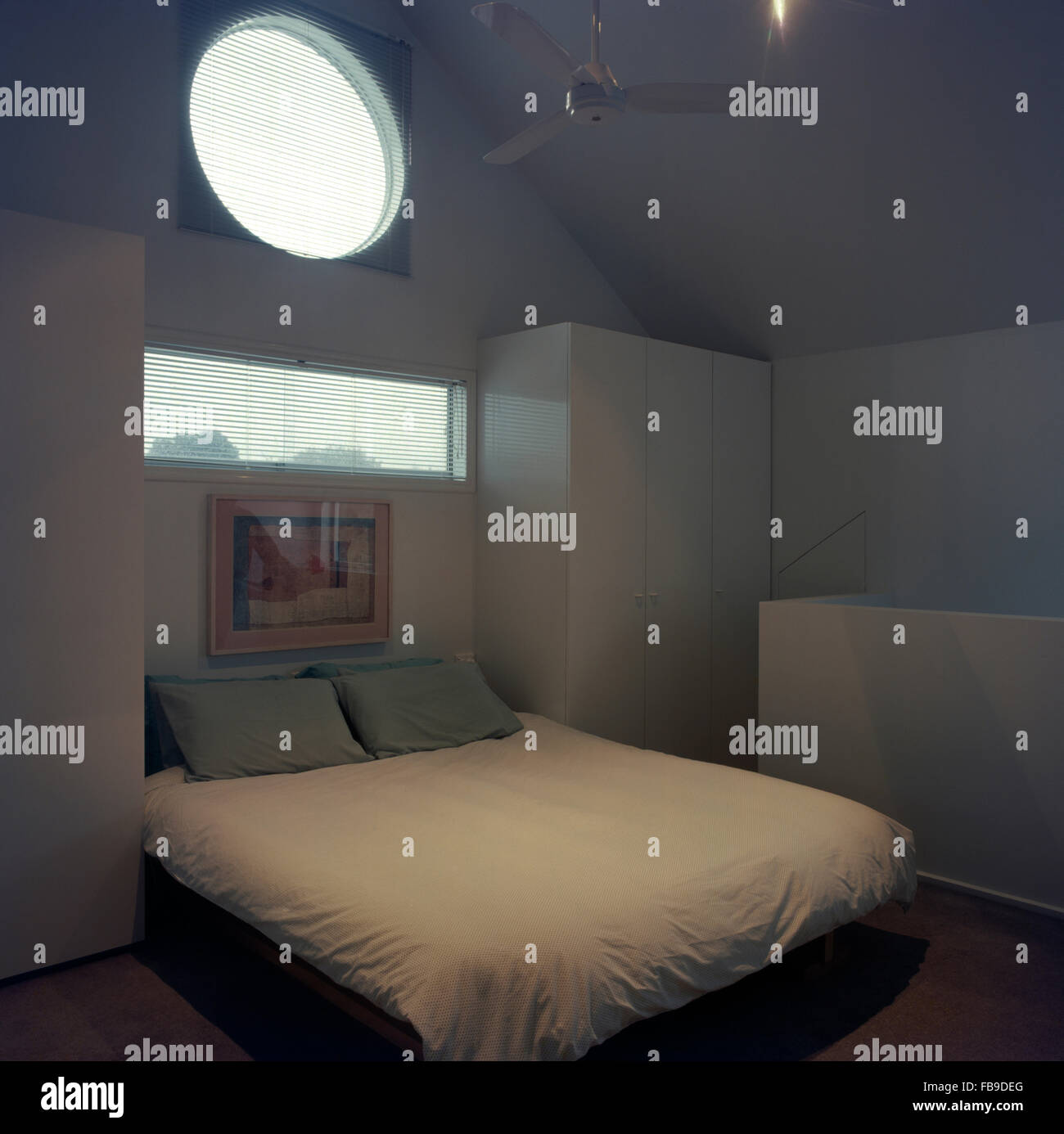 Circolare e rettangolare finestre sopra il letto con il piumone bianco degli anni novanta in camera da letto Foto Stock