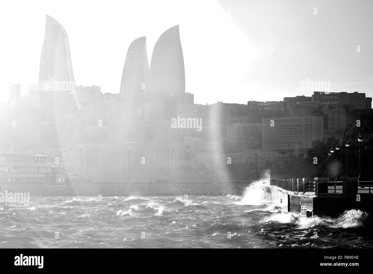 Tempestoso Mare Caspio con onde che si infrangono contro la Bulvar. Flare su torri a fiamma a Baku, capitale dell'Azerbaigian Foto Stock