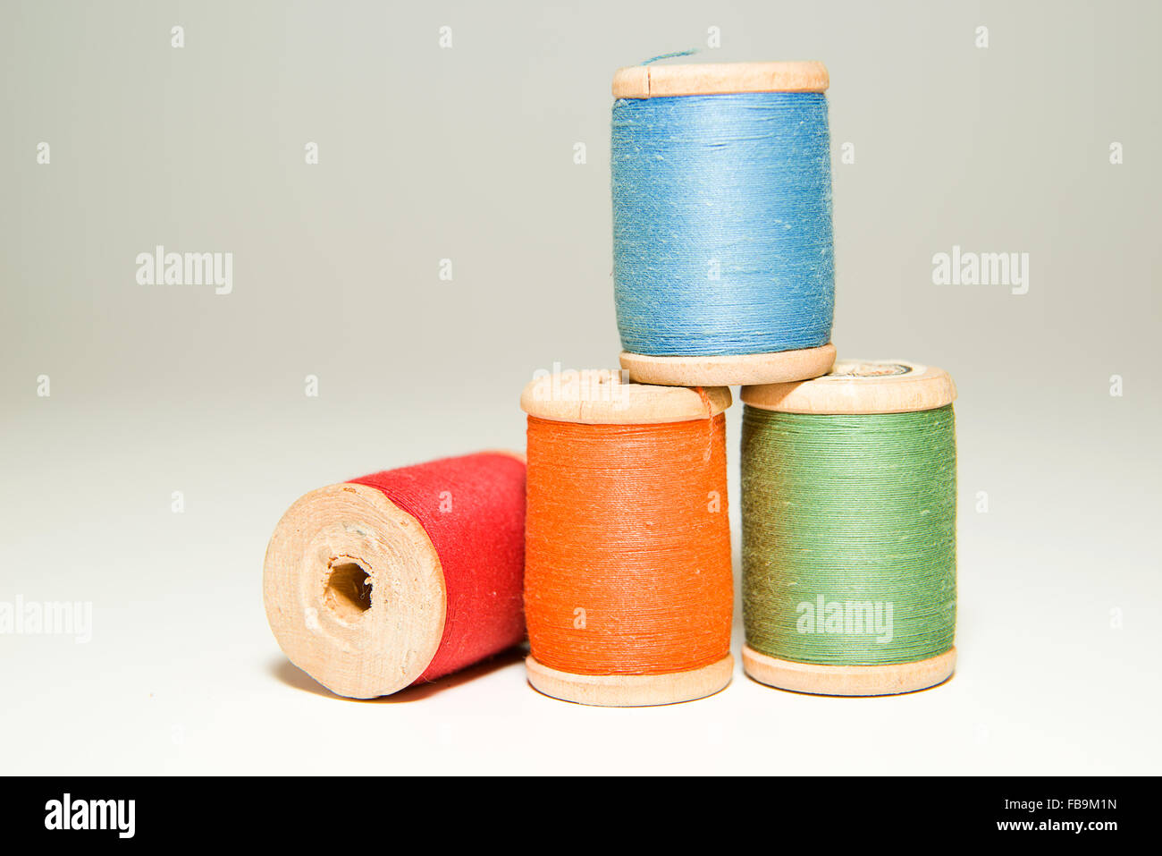 Diverse bobine di filo di diversi colori su bianco Foto Stock