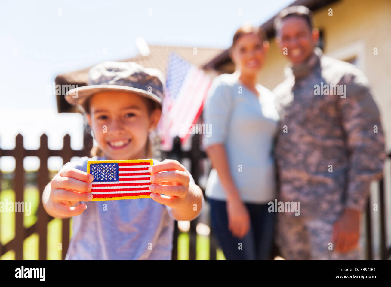 Little Girl holding bandiera americana badge nella parte anteriore dei genitori Foto Stock