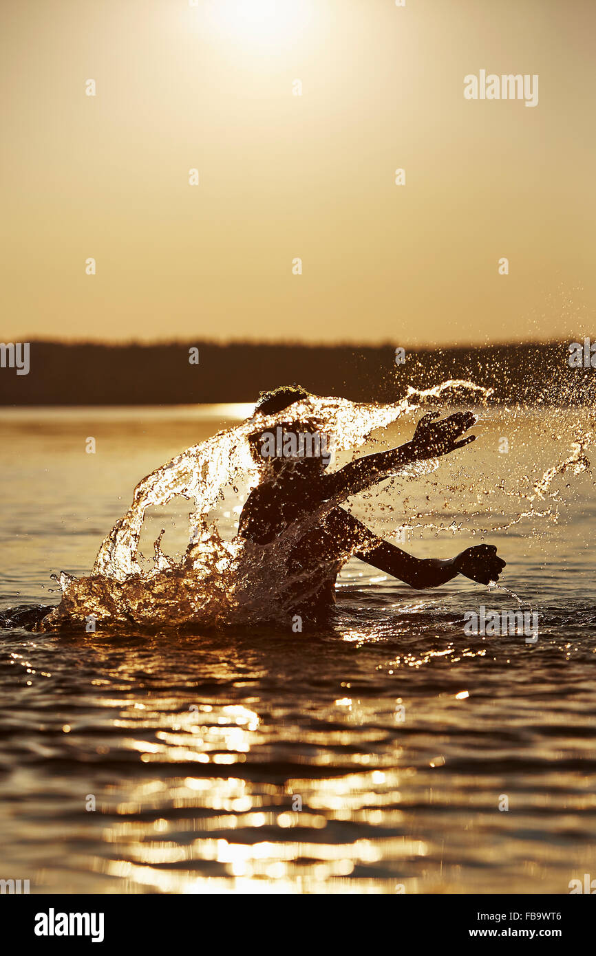 La Svezia, Vastra Gotaland, Skagern, ragazzo (10-11) spruzzi nel lago al tramonto Foto Stock