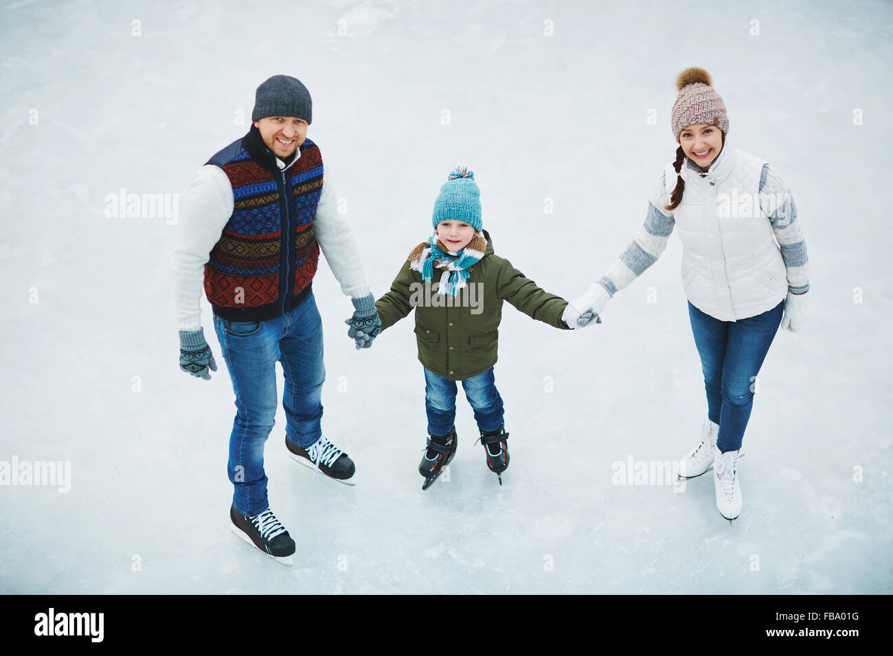 Due genitori con figlio pattinare nel pattinaggio su ghiaccio in inverno Foto Stock