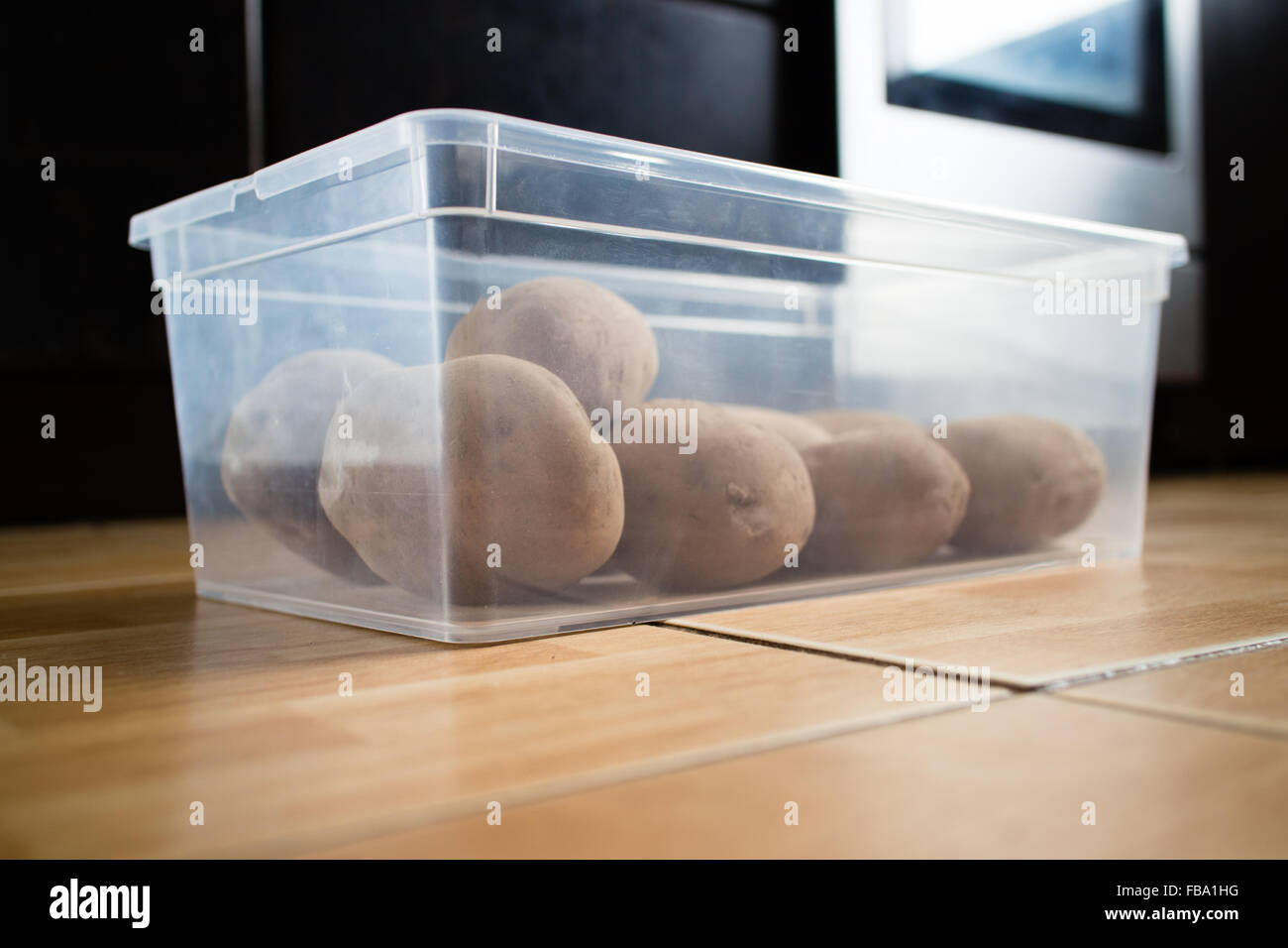 Materie le patate in un contenitore di plastica su un pavimento di cucina. Foto Stock