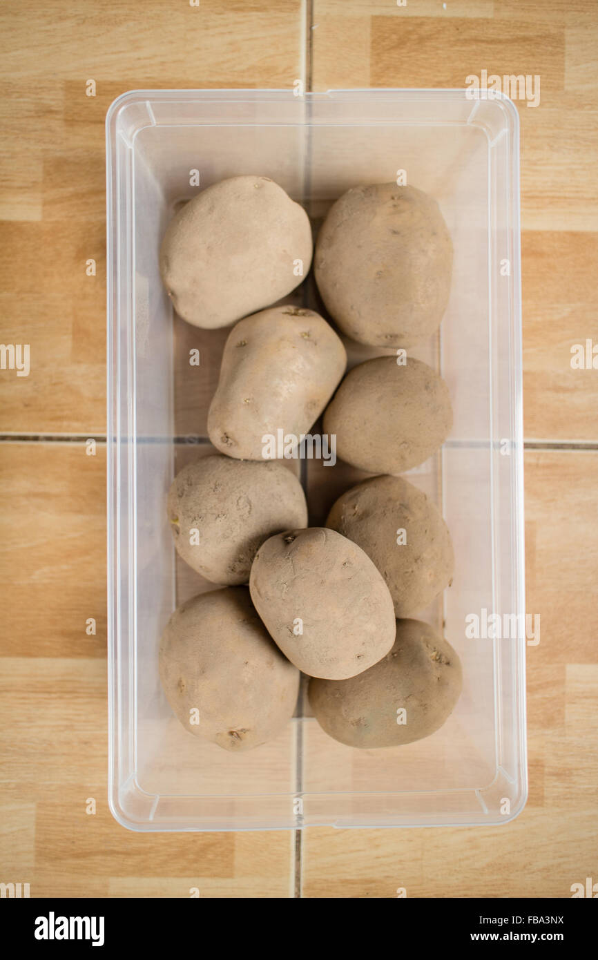 Materie le patate in un contenitore di plastica sul pavimento. Foto Stock