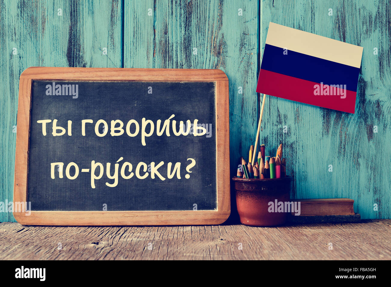 Una lavagna con la questione non si parla russo? Scritto in russo, una pentola con matite, alcuni libri e la bandiera della Russia, Foto Stock