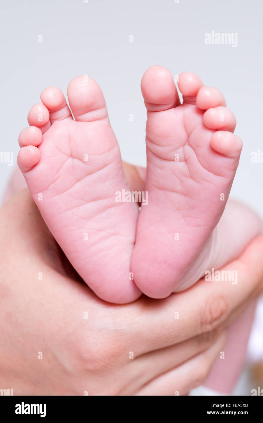 Stretta di mano che tiene i neonati piedi Foto Stock