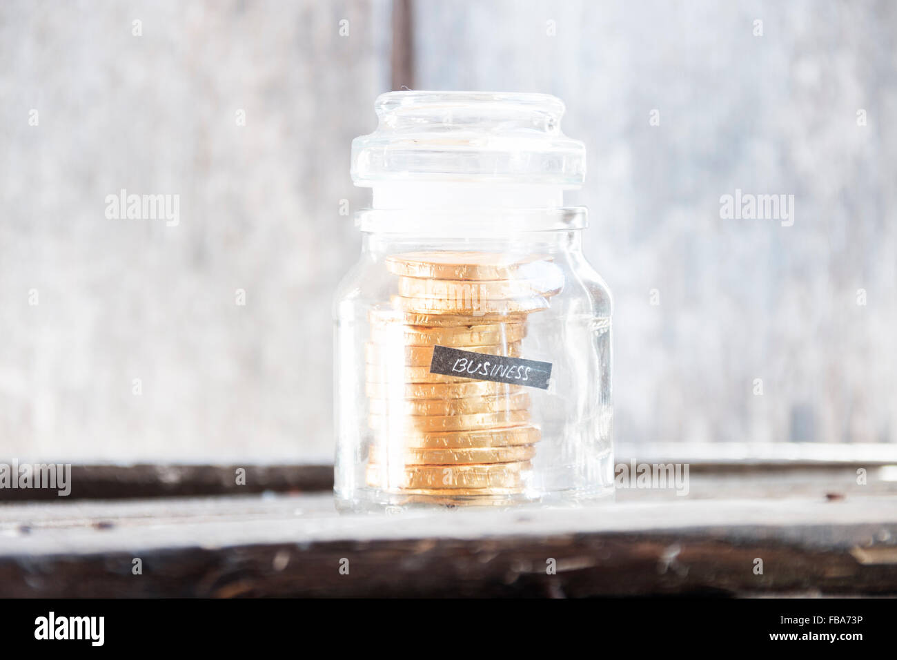 Testo aziendale e monete d'oro in una bottiglia di vetro Foto Stock