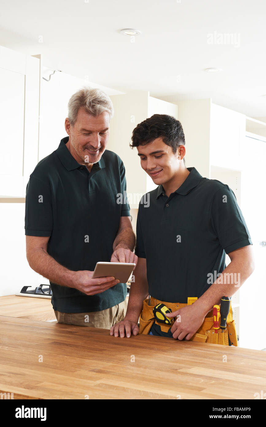 Falegname e apprendista con tavoletta digitale montaggio cucina di lusso Foto Stock