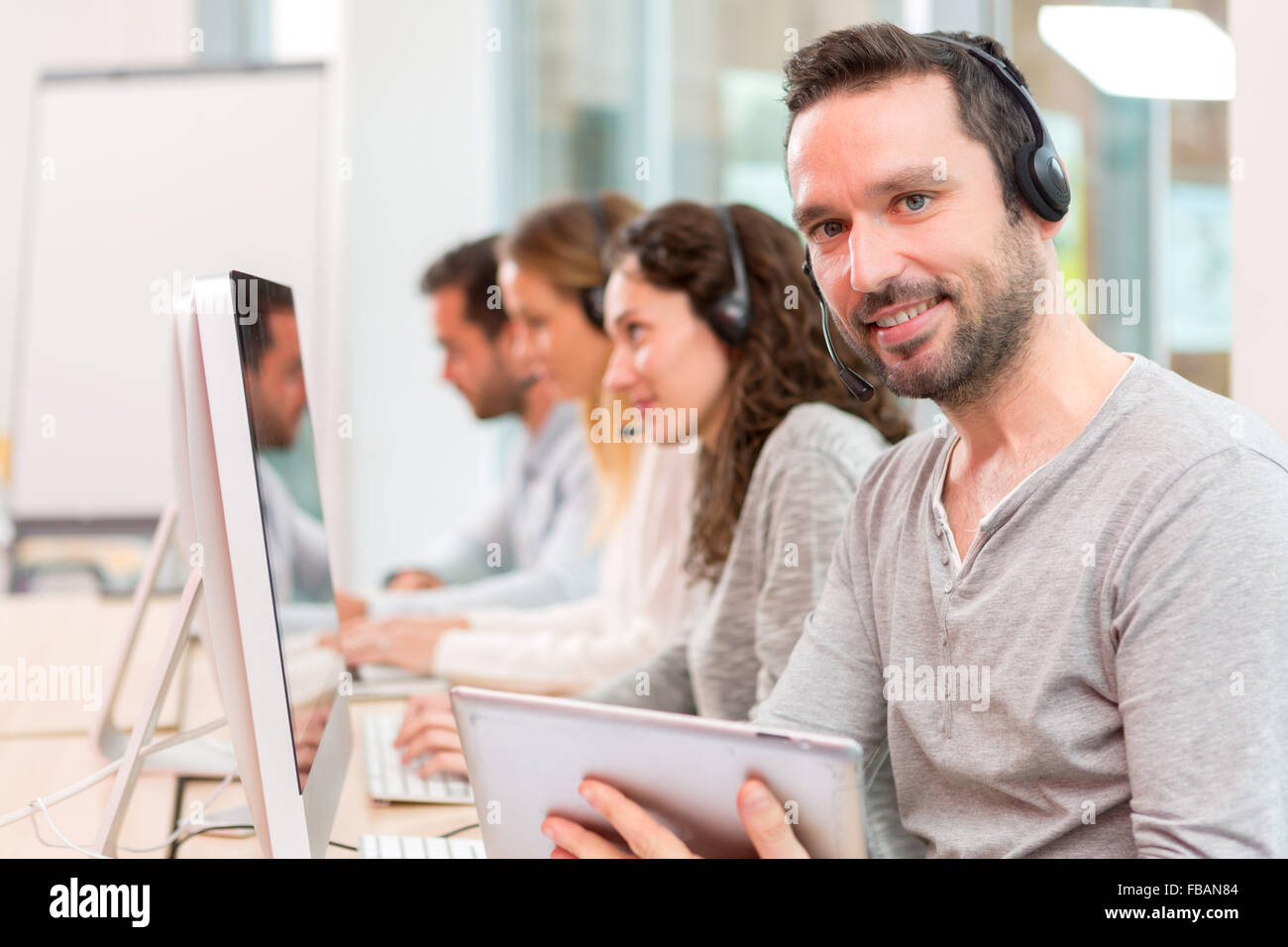 Vista di un giovane attraente uomo che lavora in un call center Foto Stock