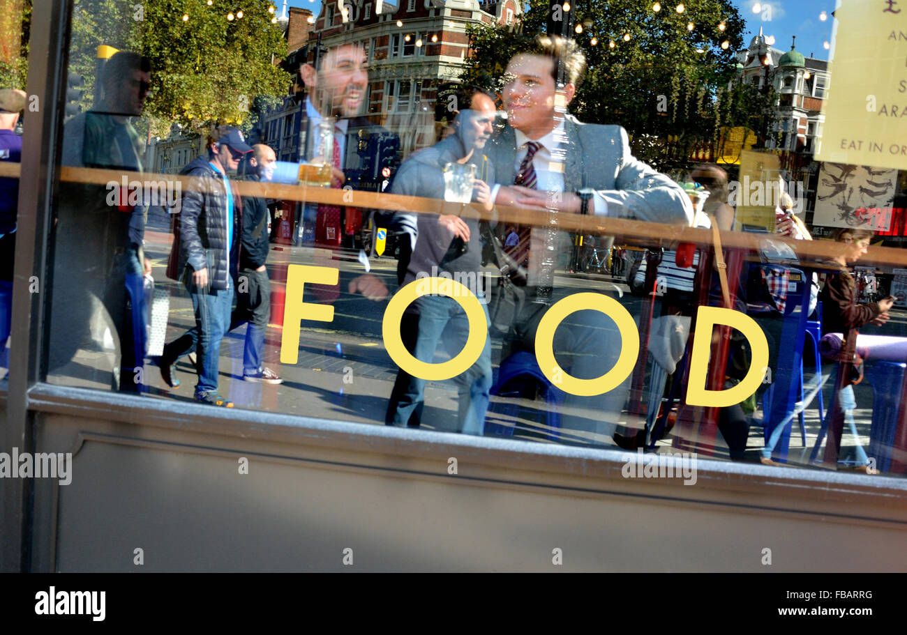 Londra, Inghilterra, Regno Unito. Riflessioni nella finestra di un ristorante con due uomini di mangiare all'interno Foto Stock