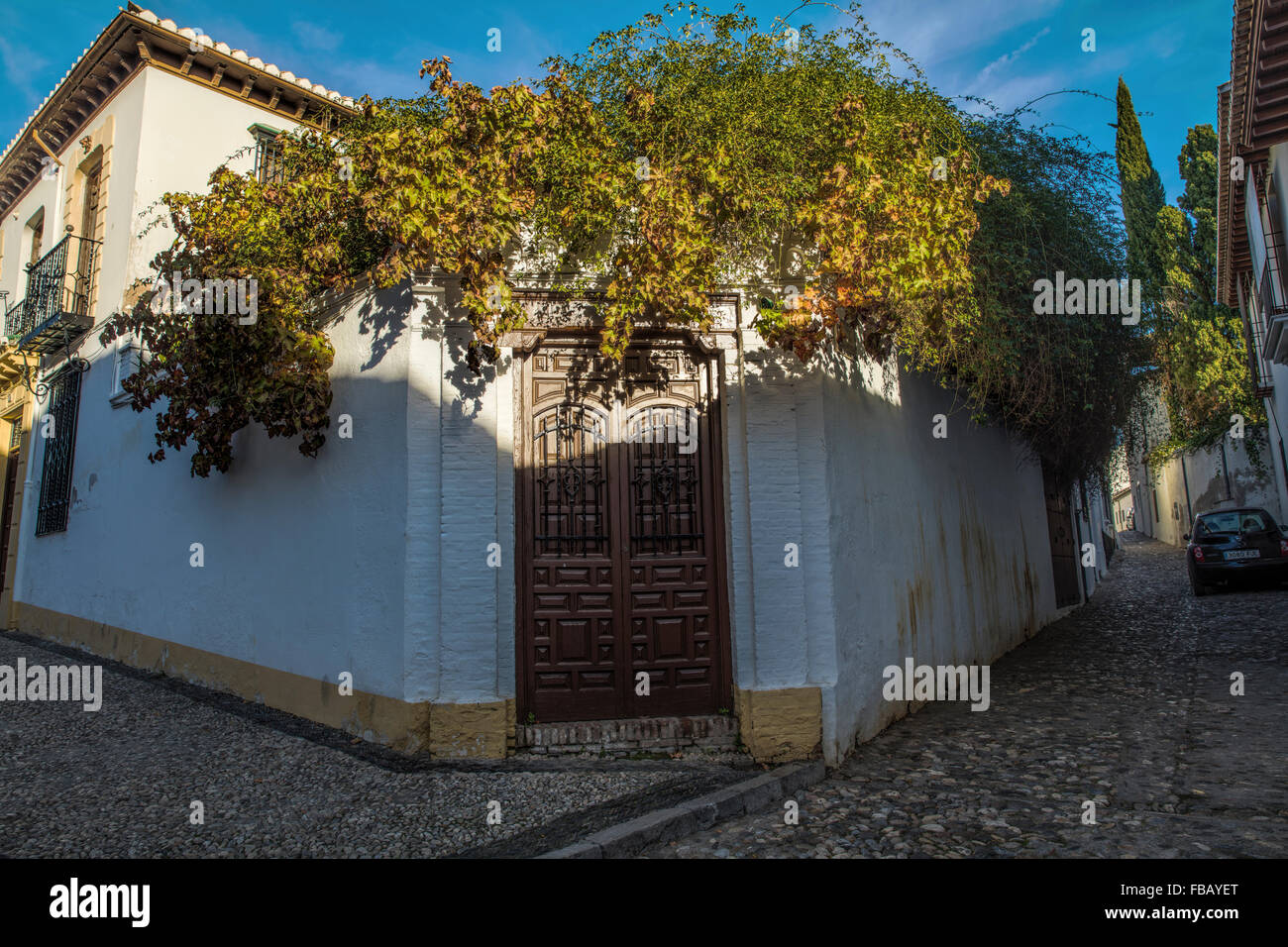 Molto piacevole casa d'angolo nell'Albaicin a Granada Spagna con il sole di sera su di uno splendido albero oltre la porta di casa. Foto Stock