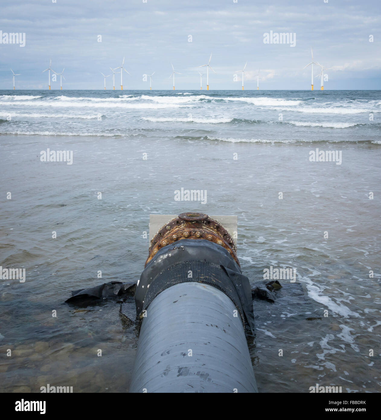 Il tubo di efflusso su Redcar spiaggia sulla costa nord est dell'Inghilterra. Regno Unito. Teesside per centrali eoliche offshore in distanza. Foto Stock