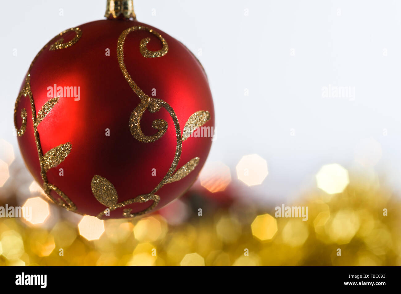 Rosso Pallina natale con oro tinsel e luci fairy dietro. Foto Stock