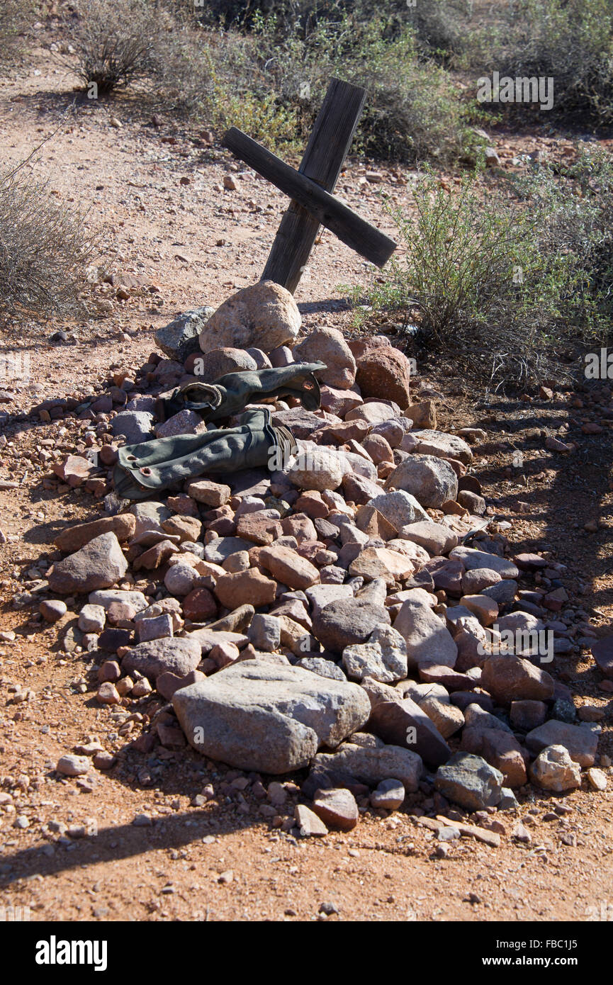 Una tomba nel deserto contrassegnati con una croce e stivali Foto Stock