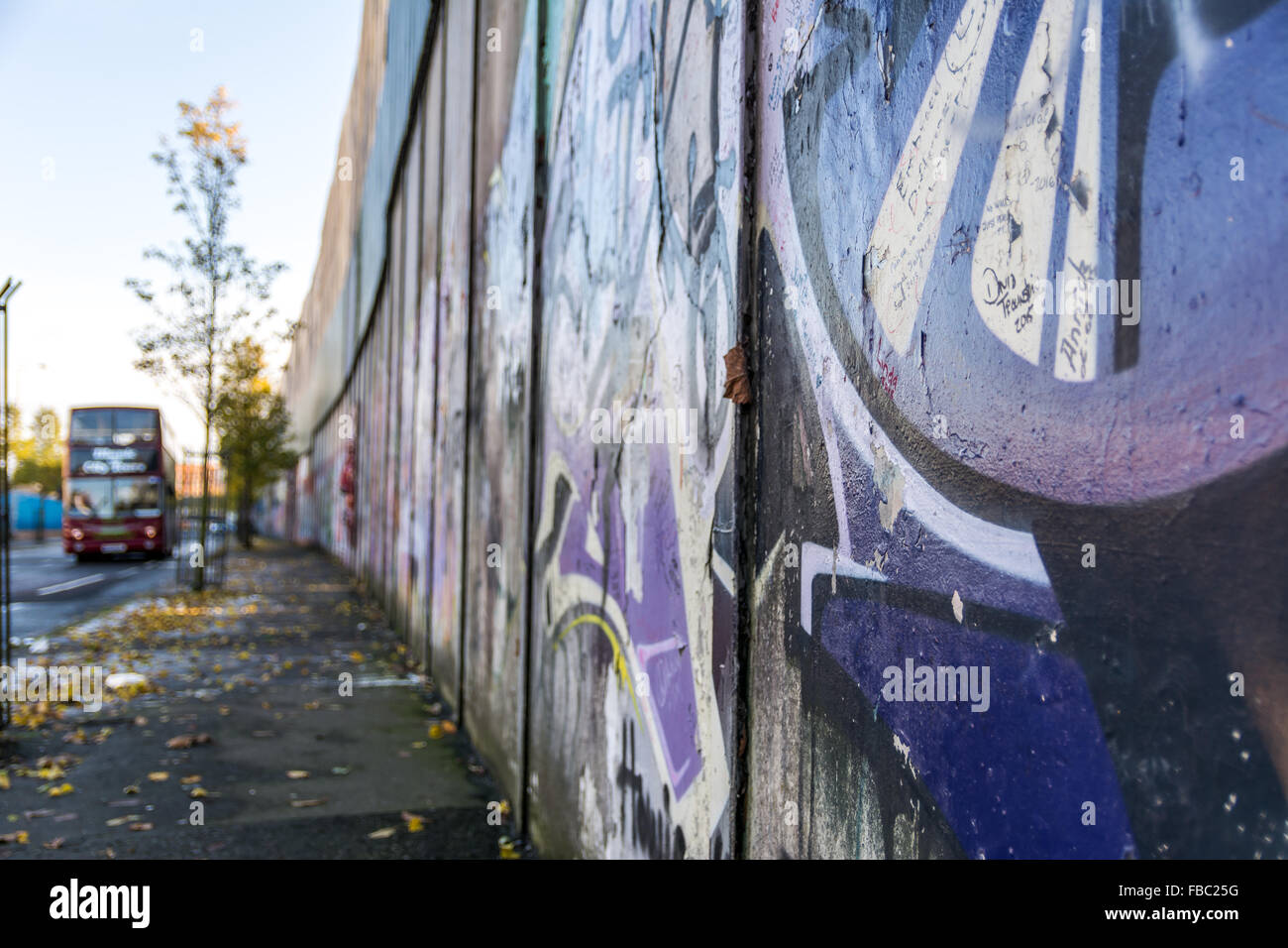 Un autobus turistico che passa lungo il Belfast parete di pace. Foto Stock