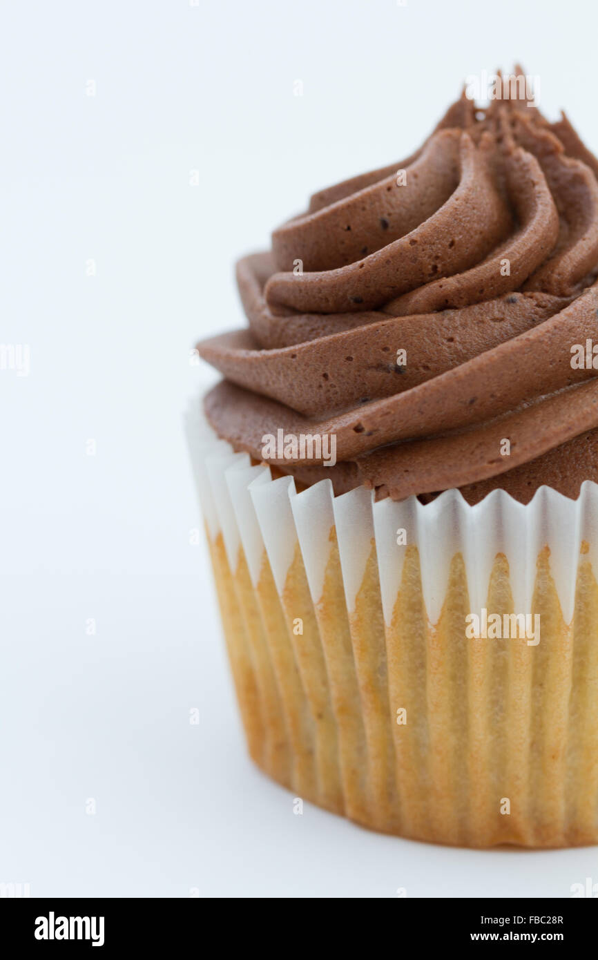 Un vicino l immagine di un cupcake al cioccolato con glassa roteato isolato su un fondo bianco. Foto Stock