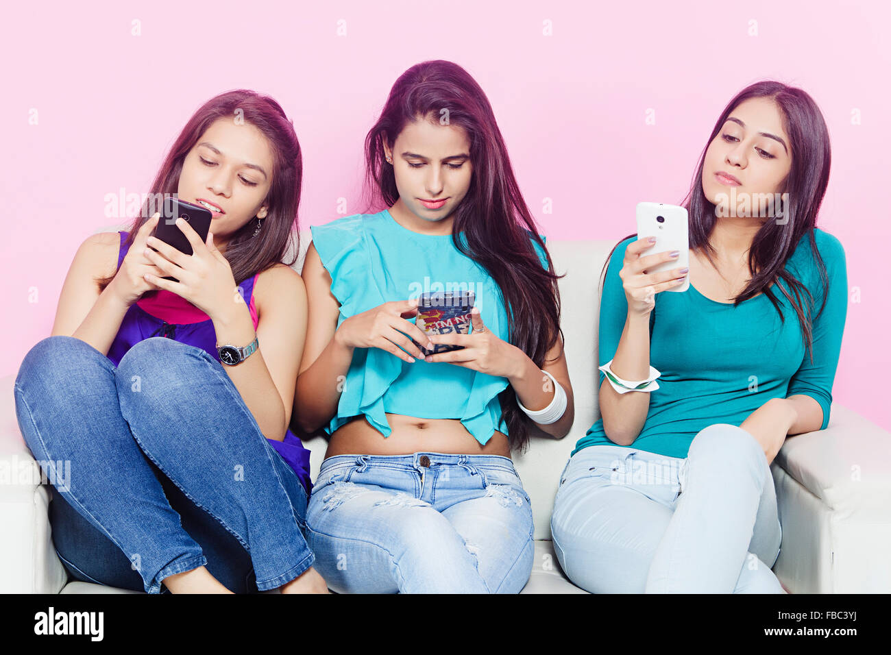 3 giovani indiani Womans amici divano Chat Telefono Mobile Foto Stock