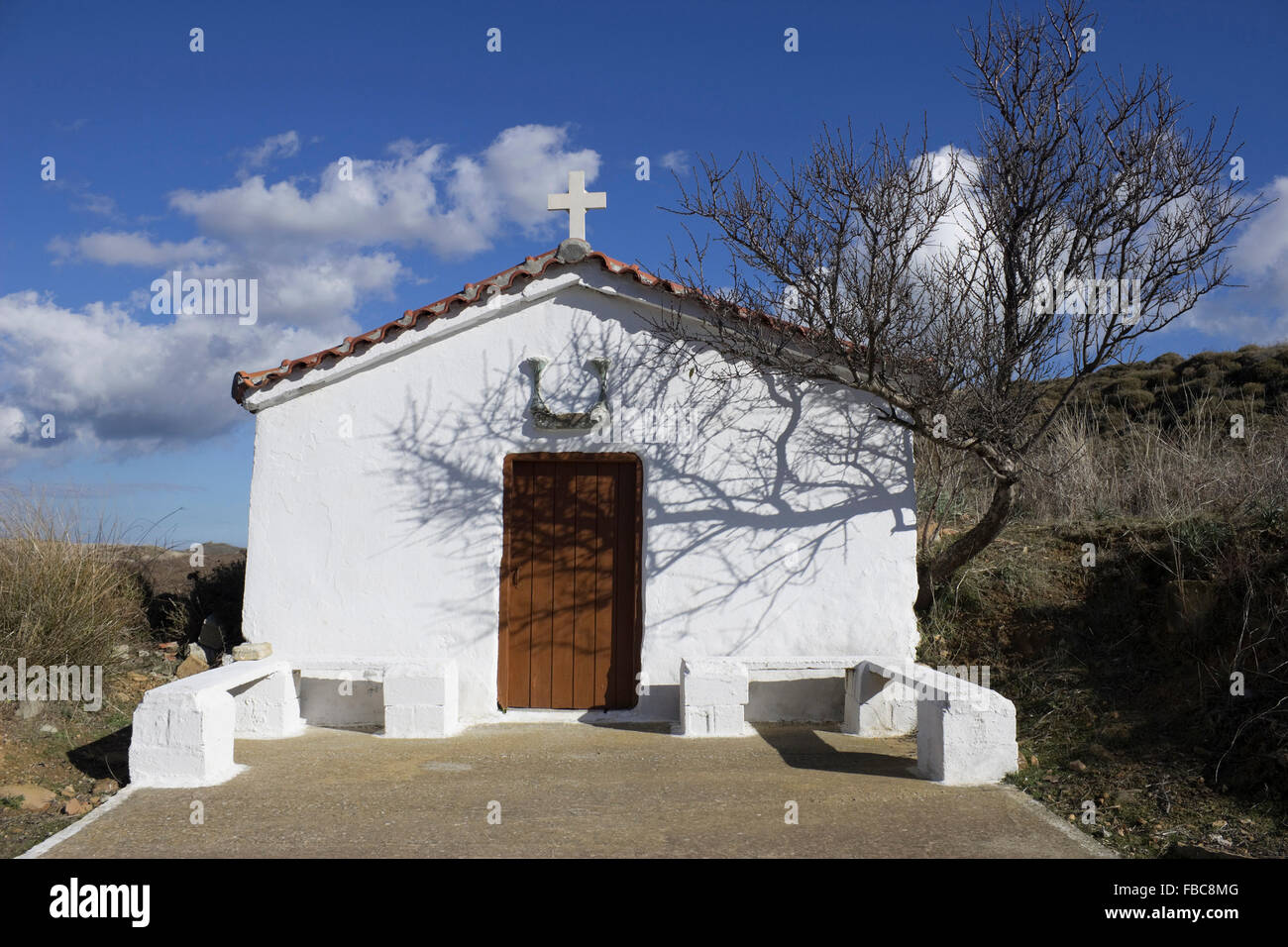 Facciata di una piccola cappella rurale imbiancata nella strada accidentata di Krinida, zona di Kotsinas, isola di Limnos, Grecia. Foto Stock