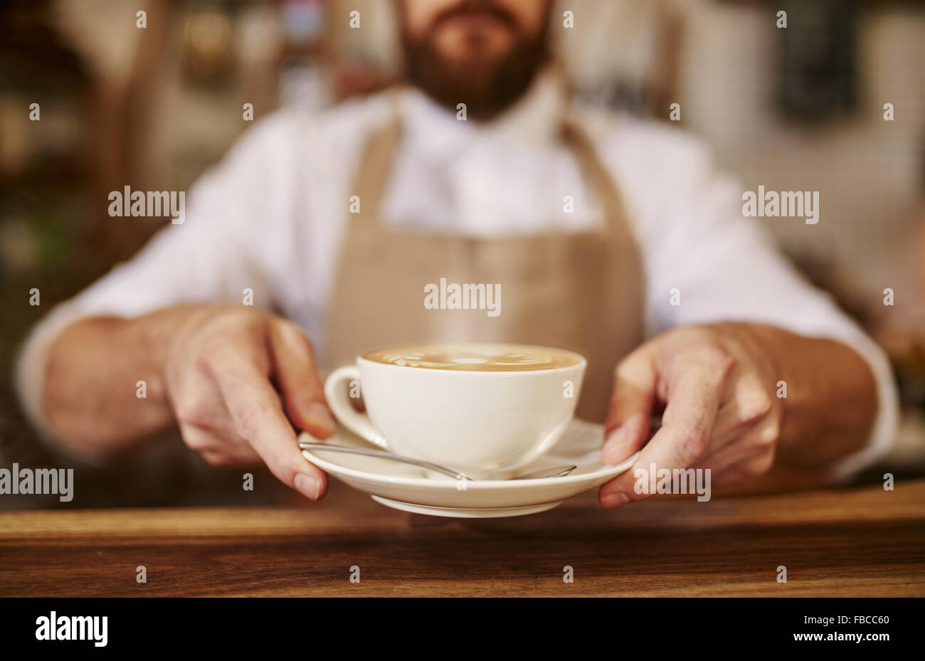 Close up dei maschi di barista serve tazza di caffè fresco. Tazza di caffè nelle mani del cameriere. Foto Stock