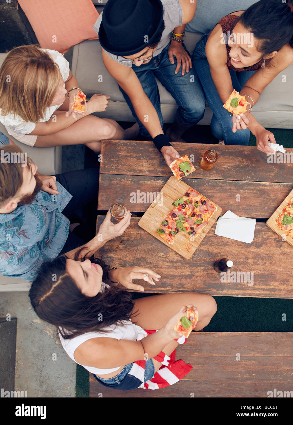 Vista dall'alto del gruppo di giovani aventi le bevande e pizza a parte. Multirazziale amici appendere fuori insieme. Foto Stock