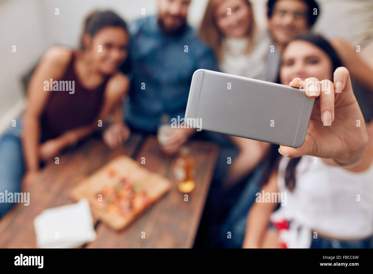 I giovani in una parte contraente di adottare qualsiasi ritratto di auto con il telefono cellulare. Focus su smart phone nella donna la mano. Un gruppo di giovani sitt Foto Stock