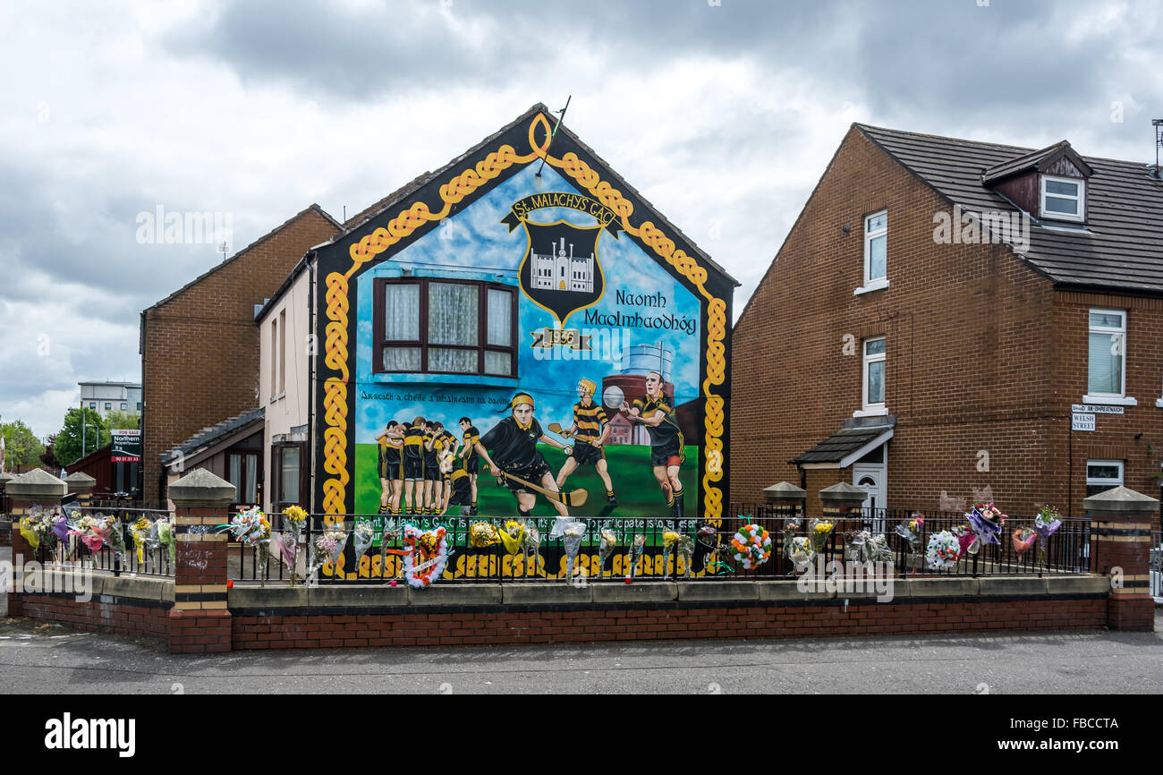 Un irlandese GAA hockey irlandese e calcio gaelico murale in mercati zona di Belfast con fiore omaggi al fine di Jock Davison. Foto Stock