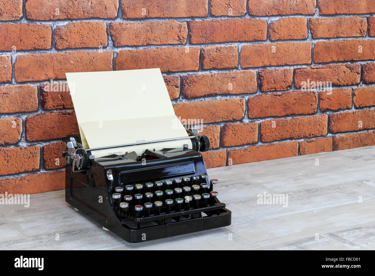 Vintage macchina da scrivere sul vecchio squallido effetto legno desk top con mattoni rossi di sfondo a parete Foto Stock