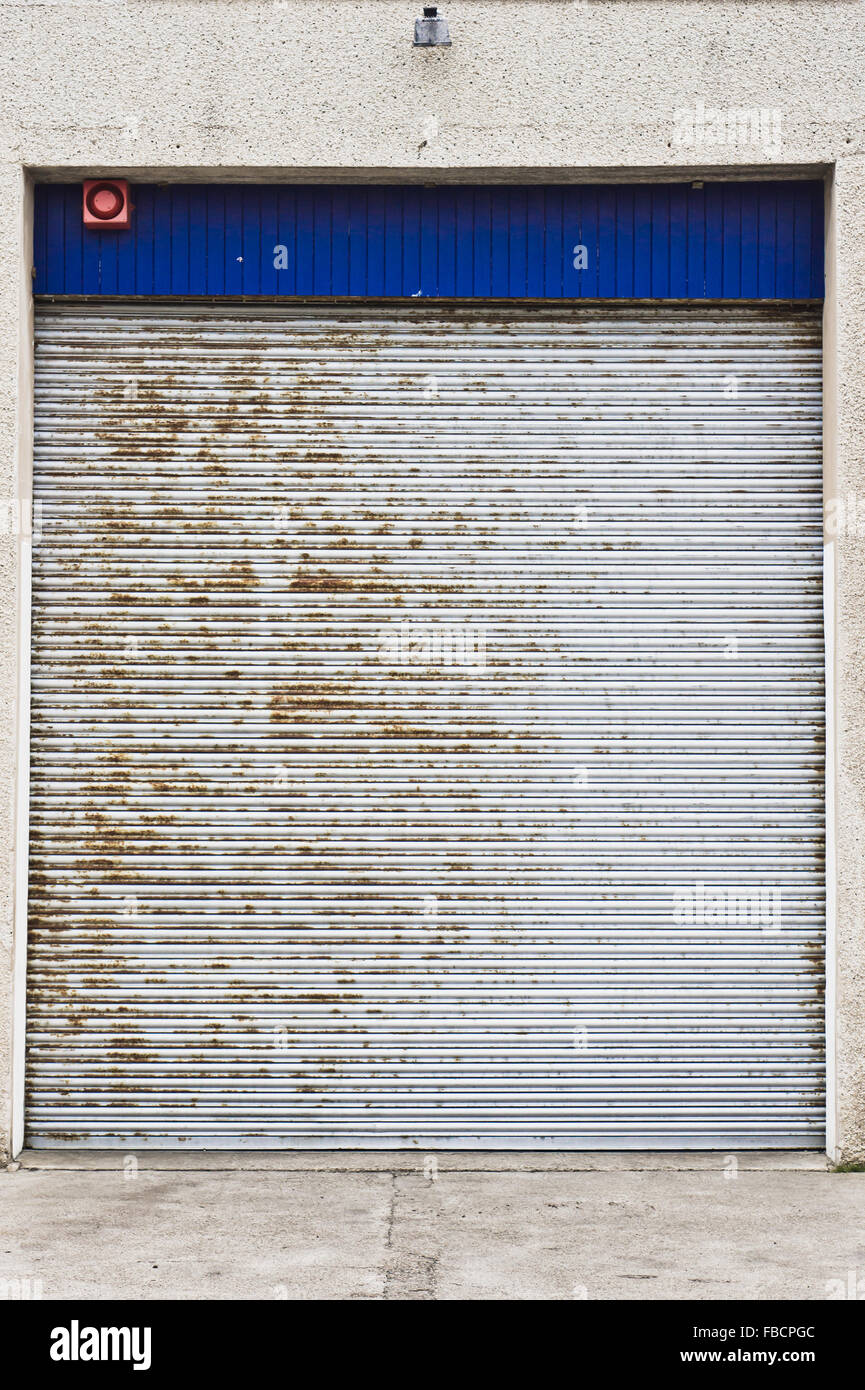 Un metallo arrugginito rullo porta nella parete esterna di un magazzino Foto Stock