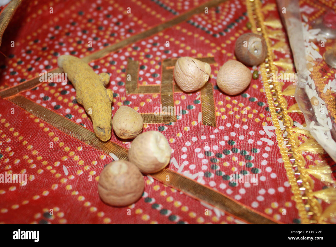 Oggetti diversi come il coleottero del dado e la curcuma prevista su un panno santo con la svastica prima di un tradizionale Jain rituale di nozze Foto Stock