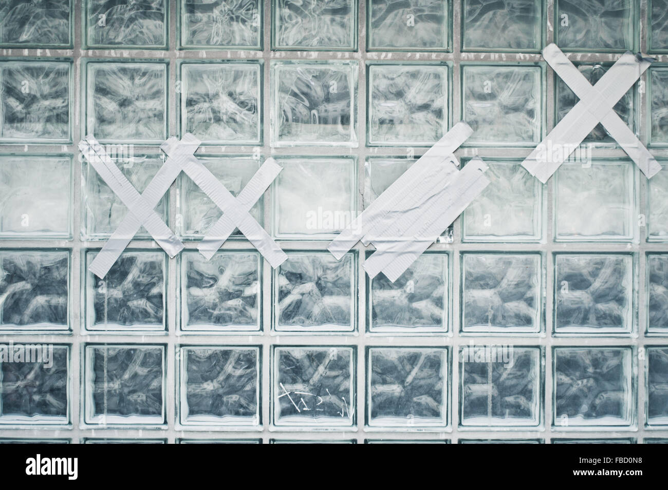 Una parete di mattoni in vetro raffazzonato con un nastro adesivo Foto Stock
