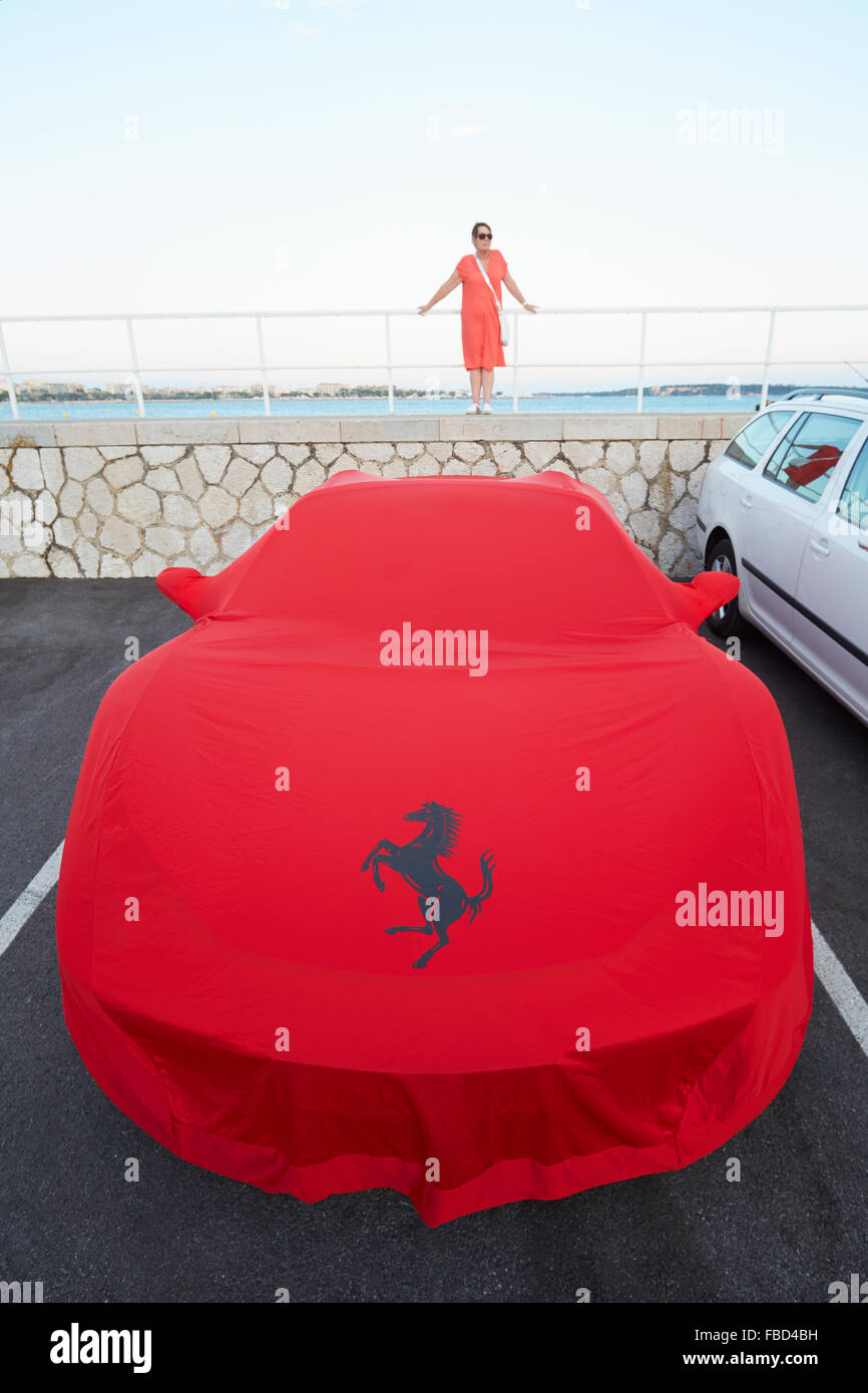 Rosso Ferrari coperta di stoffa al porto con la donna a Cannes, Francia Foto Stock